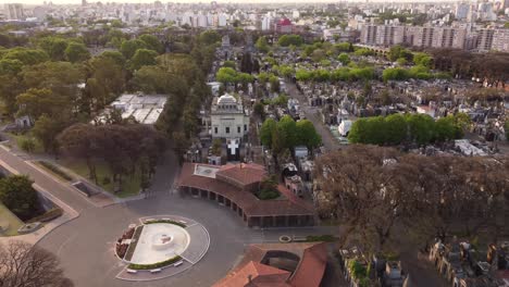 aerial flyover church of chacarita cemetery during sunset in buenos aires city - beautiful cityscape skyline in background