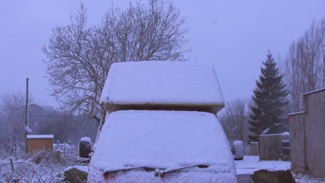 nieve en cámara lenta cayendo sobre una furgoneta cubierta de nieve en el campo