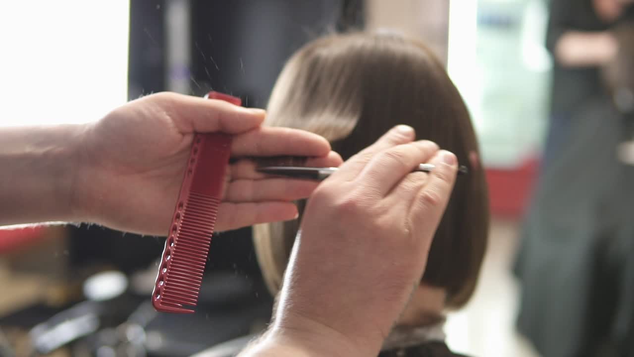 Close Up view of a hairdresser's hands cutting hair with scissors. Hairdresser at work. Beauty salon. shot in Slow Motion