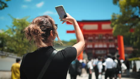 Woman-in-a-black-outfit-stands-in-a-corridor-of-red-torii-gates,-creating-a-striking-perspective-with-vibrant-colors