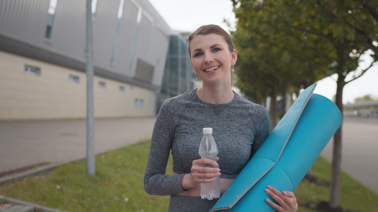mujer con alfombra de yoga y botella de agua