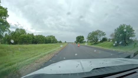 pov- conduciendo a través de una zona de construcción en una autopista a través del campo del medio oeste en un día nublado y lluvioso