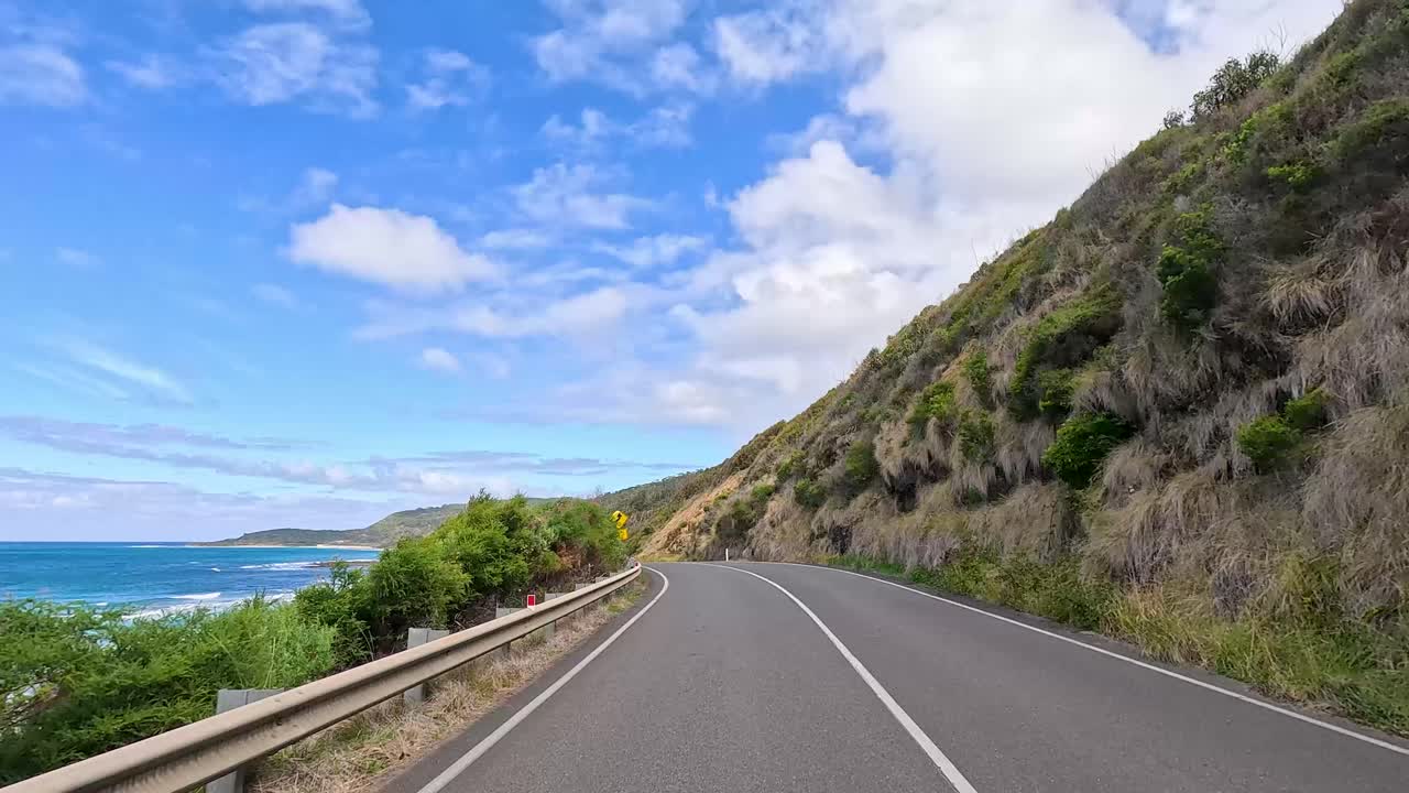 A 13-second video captures a serene drive along the Great Ocean Road, showcasing coastal views and lush greenery under a bright sky
