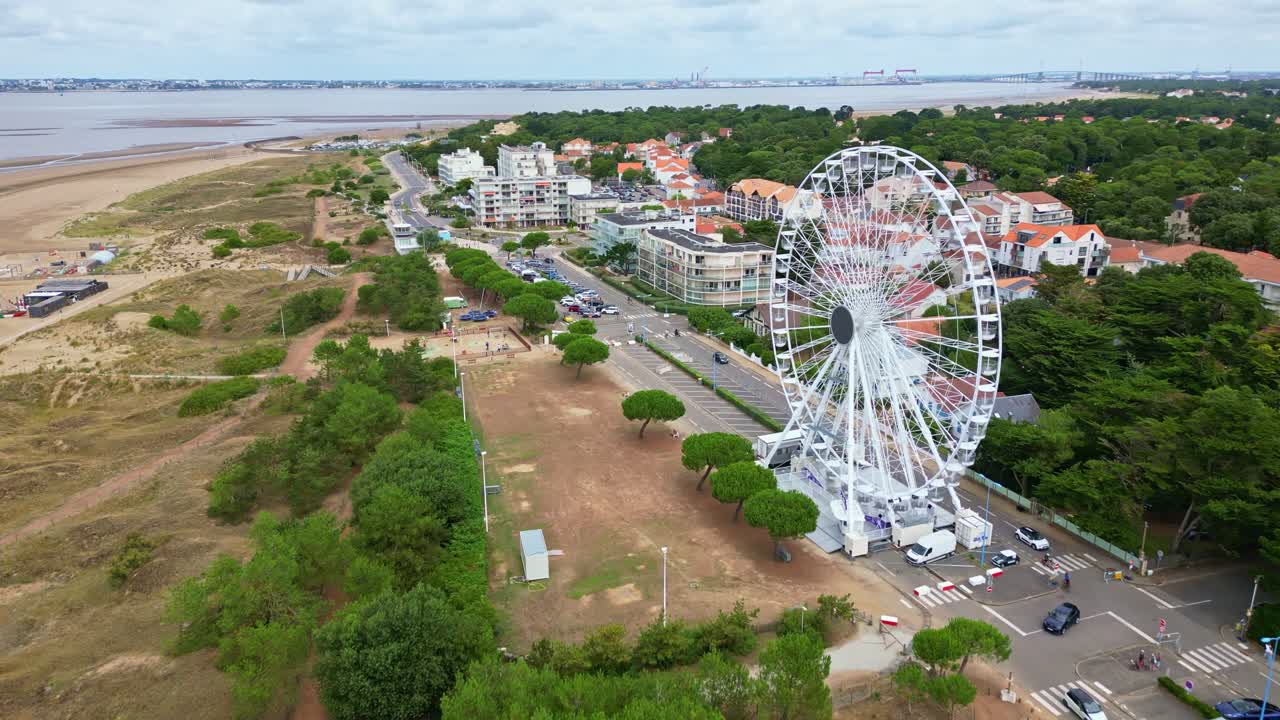 Forward drone movement of coastal amusement park with Ferris wheel and sandy beach, Saint-Brevin-les-Pins, Loire-Atlantique, France