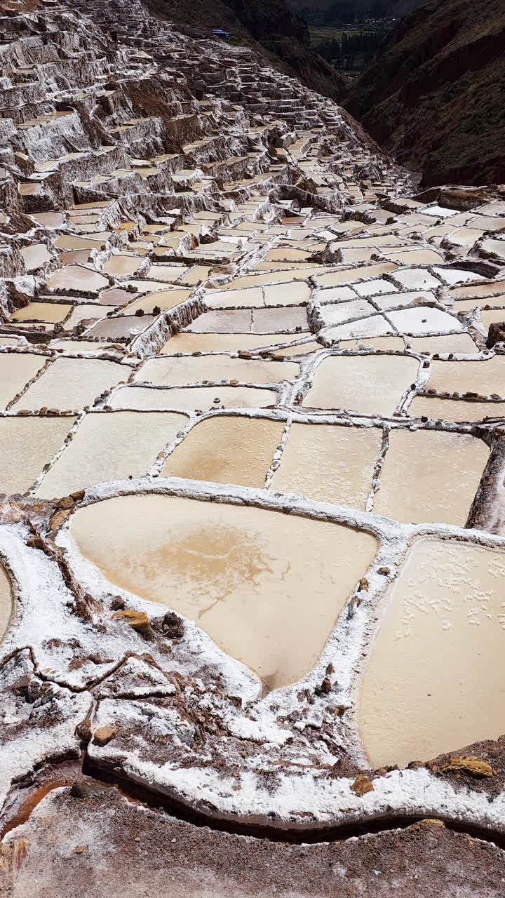 Ancient Maras Salt Flats in Peru. Showcasing the unique salt ponds and terraced landscape against a backdrop of majestic Andean mountains. Ideal for travel, culture, and nature projects