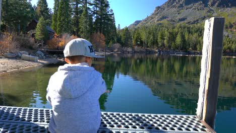 child stretching out his arms as he looks out into a beautiful lake scenery