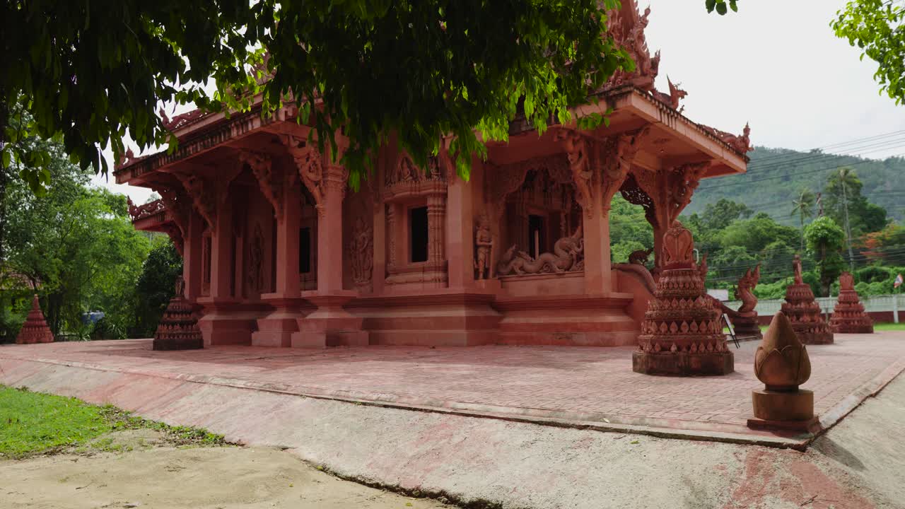 templo budista rojo rodeado de árboles verdes en tailandia