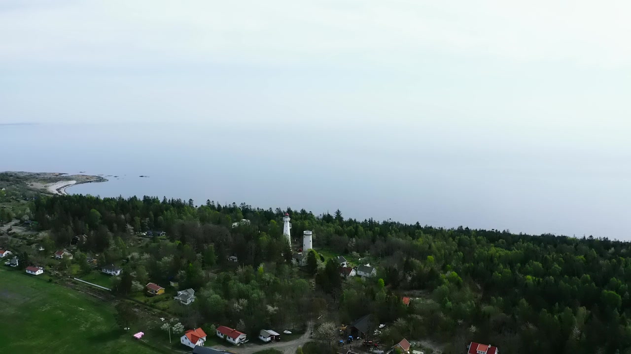 Luftfoto av fyr på skogkledd halvøy omgitt av vann