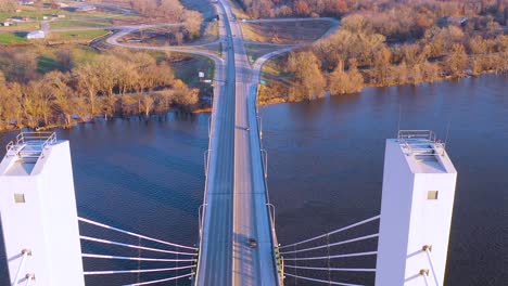 Una-Antena-De-Aviones-No-Tripulados-De-Automóviles-Y-Camiones-Cruzando-Un-Puente-Sobre-El-Río-Mississippi-En-Burlington,-Iowa,-Lo-Que-Sugiere-Infraestructura-De-Transporte-O-Transporte-Por-Camión-1