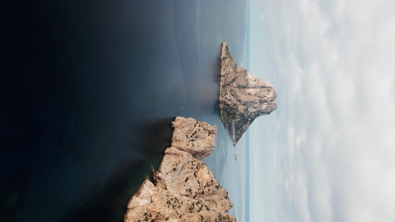 The drone flies sideways over the sea looking at Es Vedr&agrave; the small rocky island in vertical position in Ibiza Spain Aerial Footage 4K