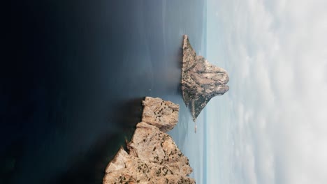 el dron vuela lateralmente sobre el mar mirando a es vedrà la pequeña isla rocosa en posición vertical en ibiza españa imágenes aéreas 4k