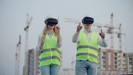dos inspectores del futuro en el sitio de construcción usan gafas de realidad virtual en el fondo de edificios y grúas