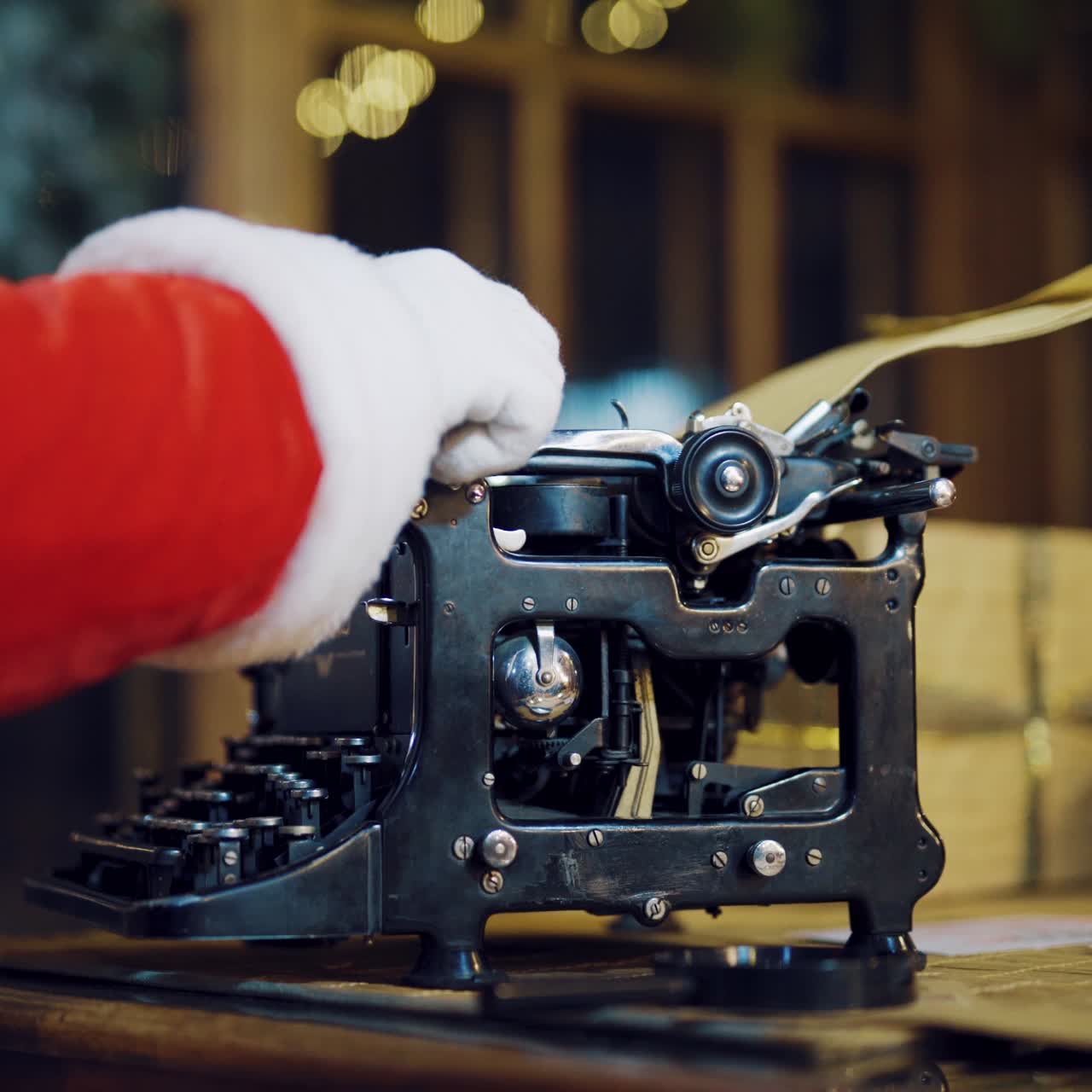 Santa Claus is sitting at the table and typing a letter of congratulations for the New Year on the typewriter in the room on a blurred background. Close-up