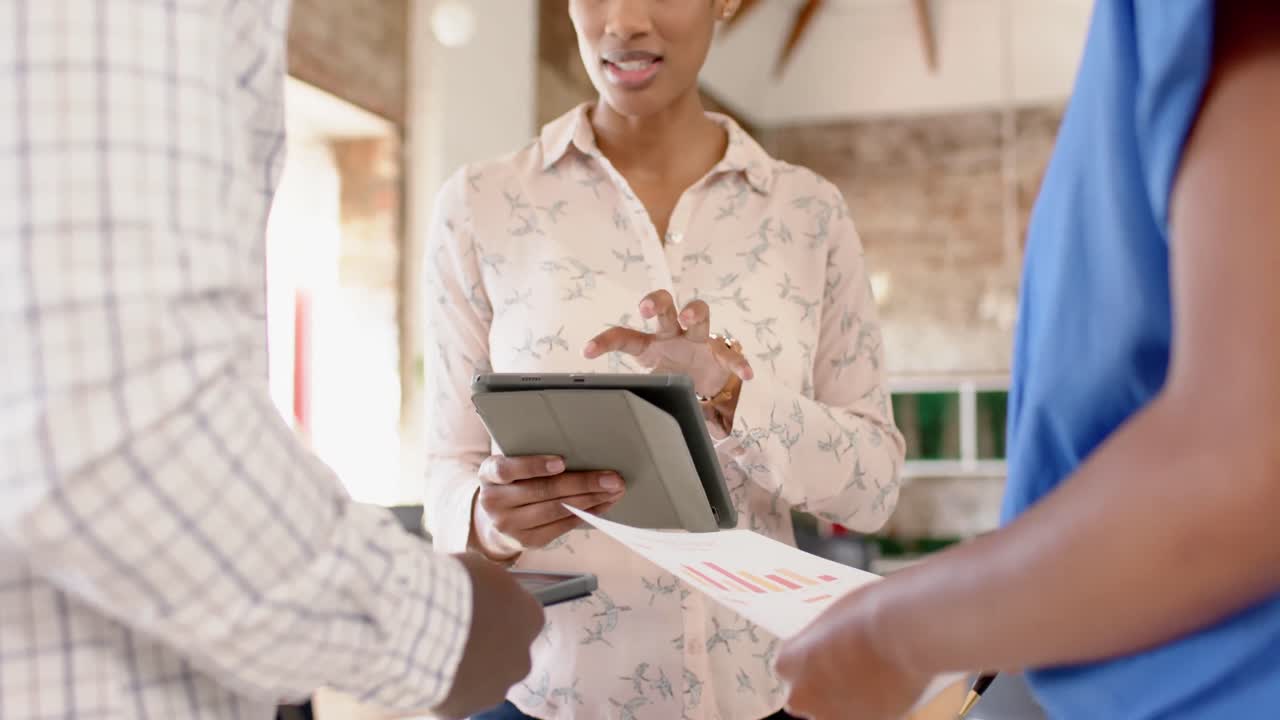 felices colegas afroamericanos usando tableta y discutiendo el trabajo en la oficina, cámara lenta