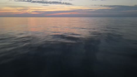 Lake-Erie-at-sunset-in-Erie,-Pennsylvania-with-low-drone-shot-over-water,-breaker-and-buoy