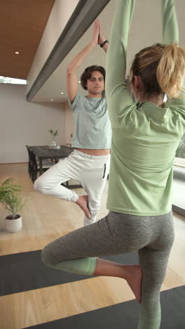 vertical video: couple practicing yoga together at home, balancing on yoga mats