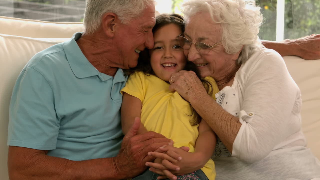 Nonni che baciano la nipote sul divano