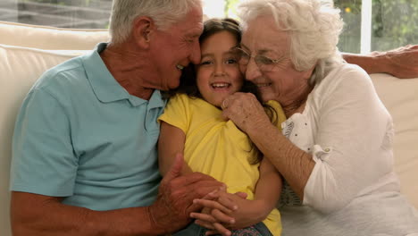 los abuelos besan a la nieta en el sofá.