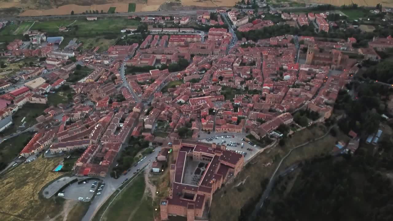 Capturing an aerial view of Sigüenza in Guadalajara, Spain, revealing the uniformity of red roofs and the striking medieval castle amidst the town's rich architectural heritage