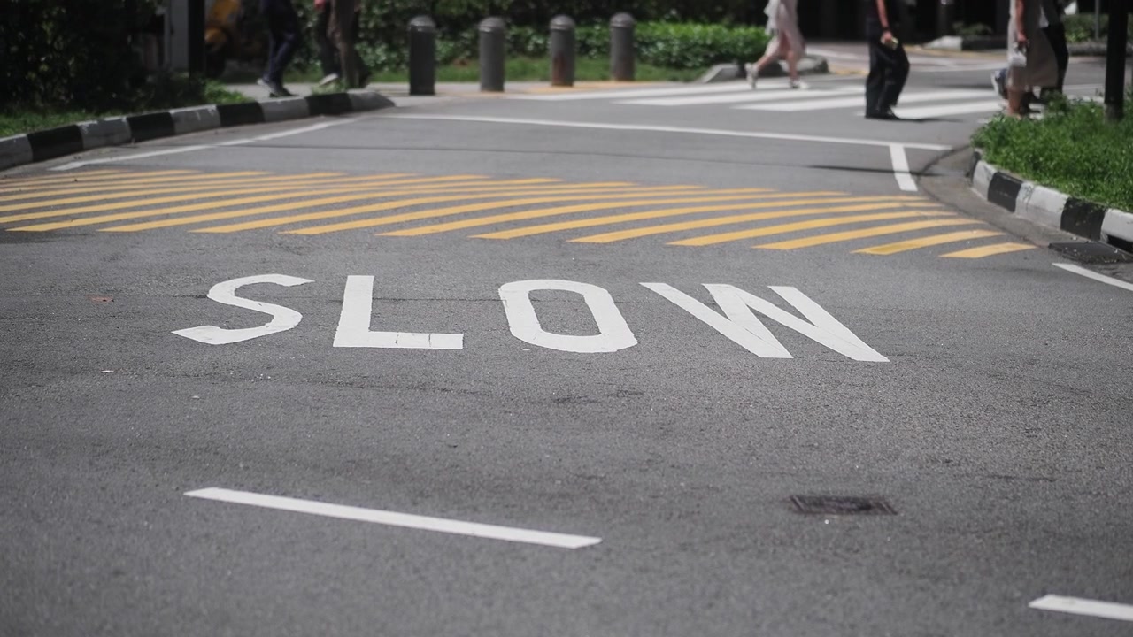Pedestrians Crossing Street with Slow Sign Painted on Asphalt