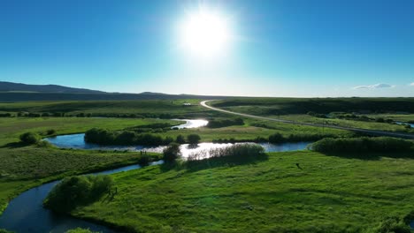 winding stream flowing through lush green fields during sunrise in driggs, teton county in idaho, usa