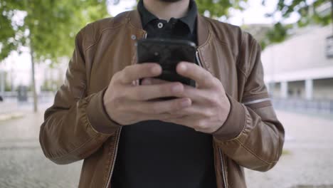 Cropped-shot-of-young-man-using-smartphone-during-stroll.