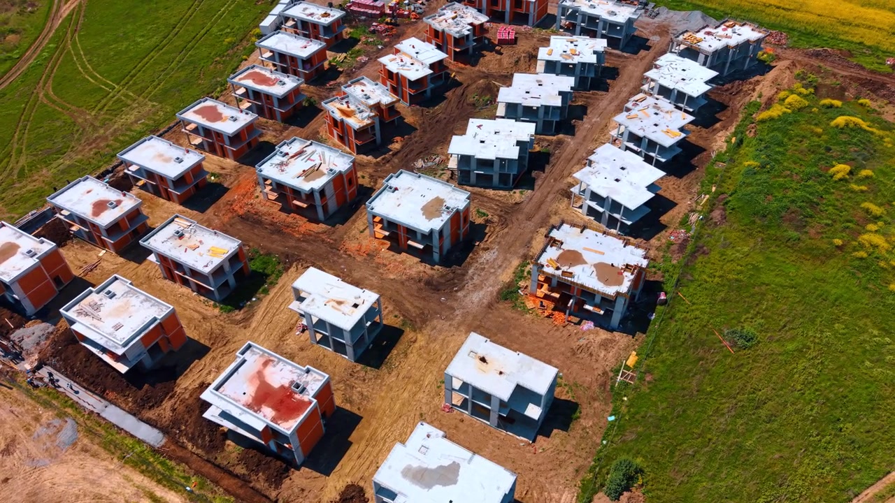 File di case residenziali in costruzione viste dall'alto con un drone. Vista aerea dall'alto che mostra file di scheletri di edifici in cemento su terreno sterrato