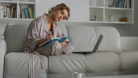 chica estudiando en casa tomando notas de cerca. mujer cansada bostezando trabajando en el sofá.