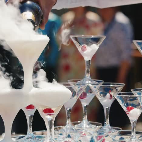 the waiter in a white shirt pours wine into the pyramid from the glasses