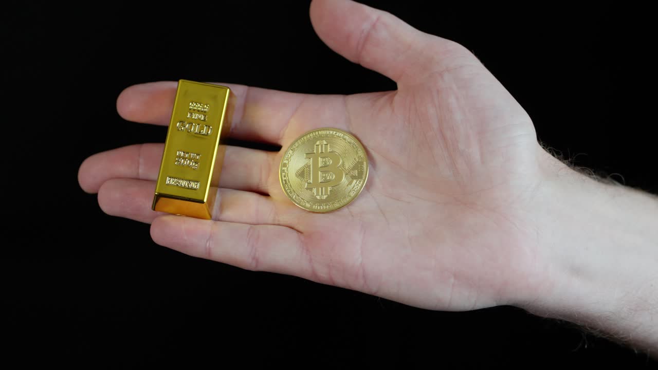 Person holds bitcoin and gold bar in hand, comparing the two different forms of currency.