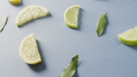 video of slices of lemon and mint leaves lying on blue background