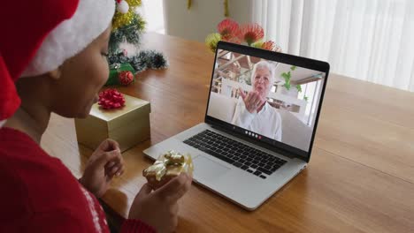 Mujer-Afroamericana-Con-Sombrero-De-Santa-Usando-Una-Computadora-Portátil-Para-Una-Videollamada-Navideña-Con-Una-Mujer-En-La-Pantalla