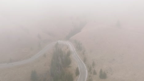 flying through foggy weather over rural road in bucegi mountains landscape, romania