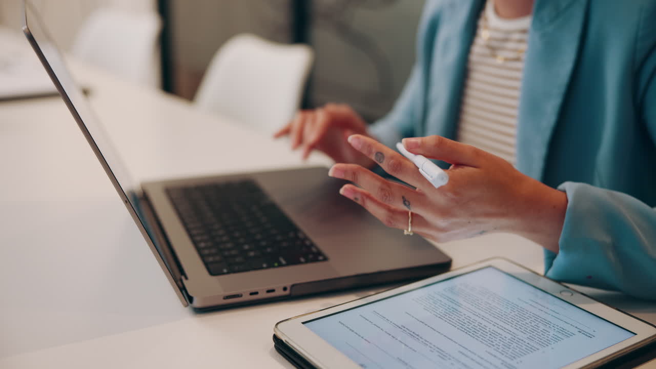 una mujer de negocios trabajando en una computadora portátil y una tableta en un entorno de oficina.
