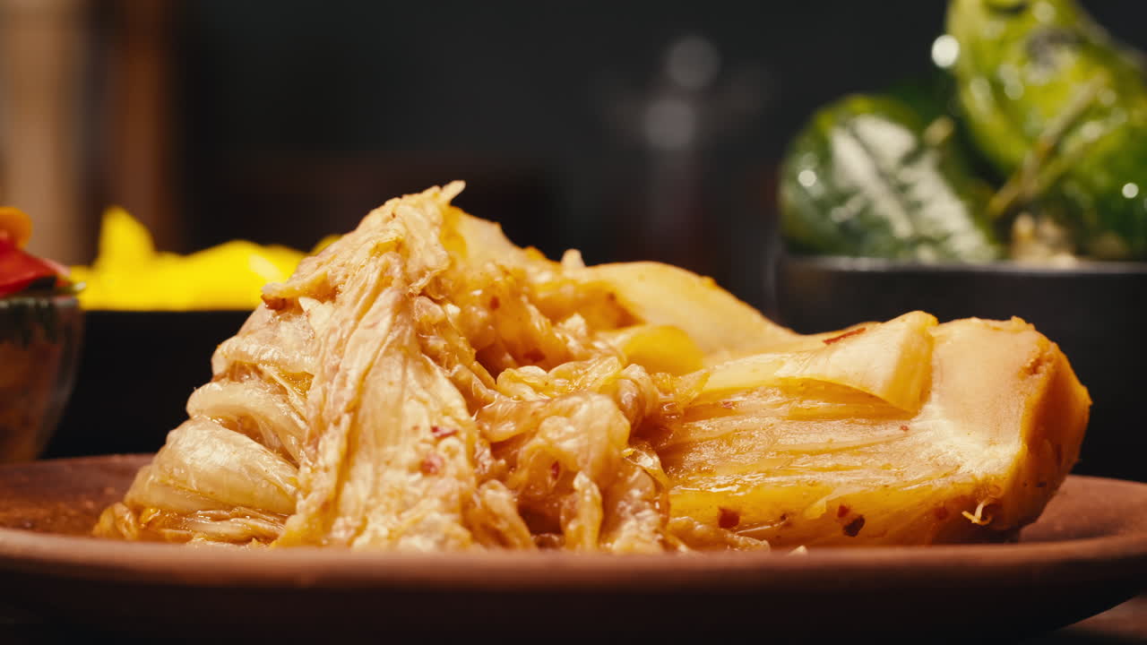 Taking a little bit of fermented spicy cabbage kimchi with chopsticks close-up. Preservation of vegetables in glass jars. Fermentation preserved kimchi cabbage with spices macro. Asian cuisine.