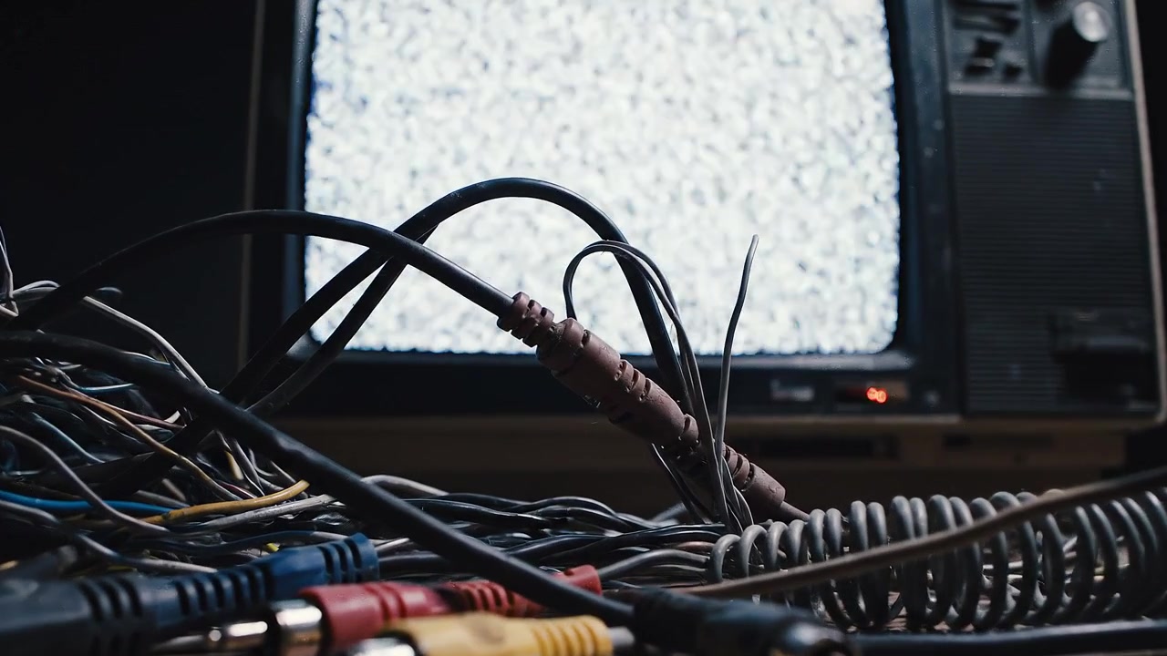 Vintage television with static screen and tangled mess of cables