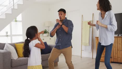 Feliz-Familia-Hispana-Con-Su-Hija-Bailando-Divirtiéndose-En-La-Sala-De-Estar