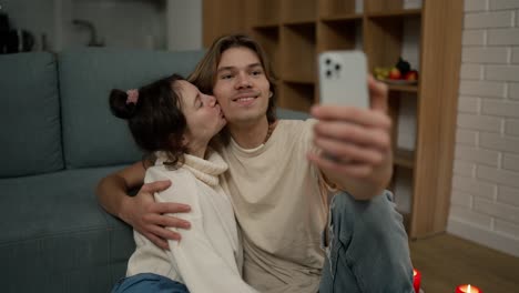 lovely couple sitting on the floor together, taking selfie with smartphone