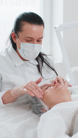terapeuta de cosmetología haciendo mujer relajante spa masaje facial con las manos en el salón de desintoxicación y curación