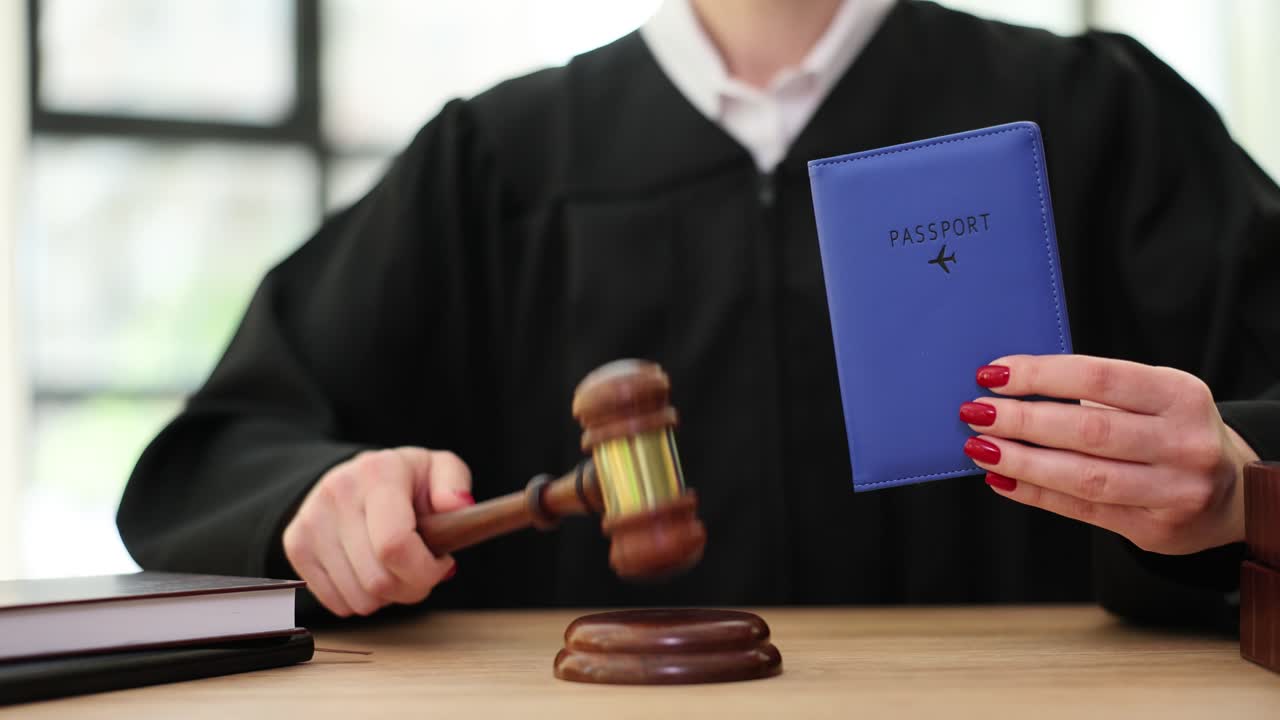 Giudice batte il martelletto su un blocco sonoro tenendo un passaporto in mano.