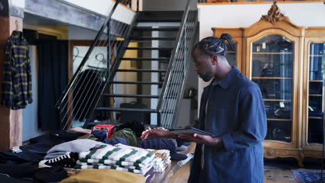 propietario masculino de una tienda de moda que utiliza una tableta digital para comprobar el stock en la tienda de ropa