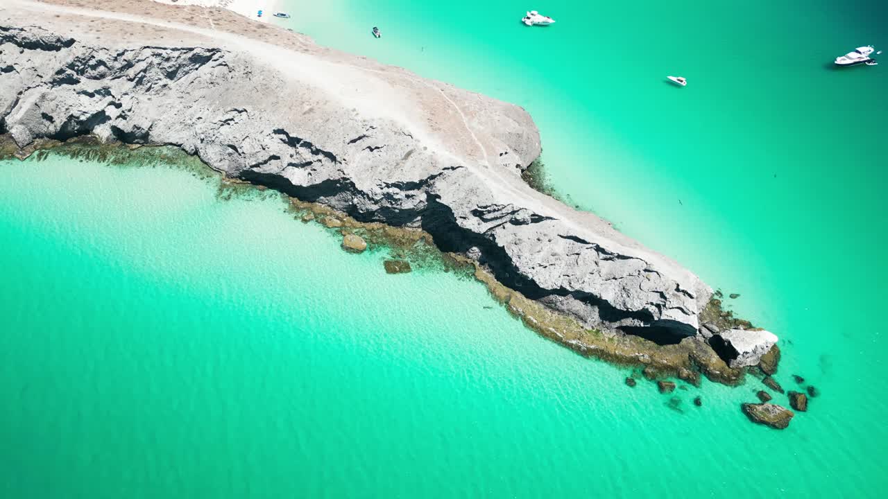 A beach with turquoise water, rocky coastline, and boats near la paz, mexico, aerial view