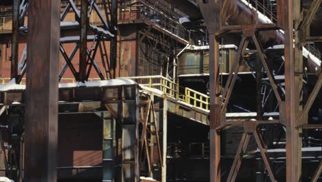 Abandoned-rusting-complex-industrial-building,-with-metal-pipes,-platforms,-rusted-steel-beams-and-supports