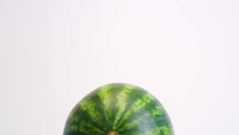 top half of watermelon spinning in circle on white backdrop in slow motion