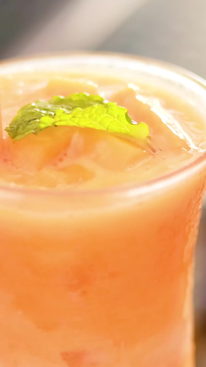 Mescolando una bevanda fresca al succo di mango guarnita con una foglia di menta a Phuket