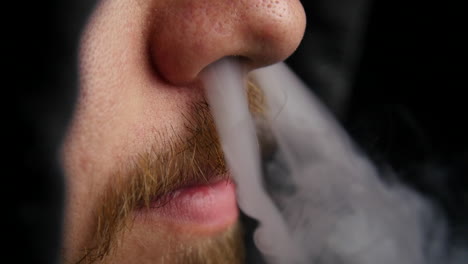 hombre encapuchado exhala vapor por la nariz