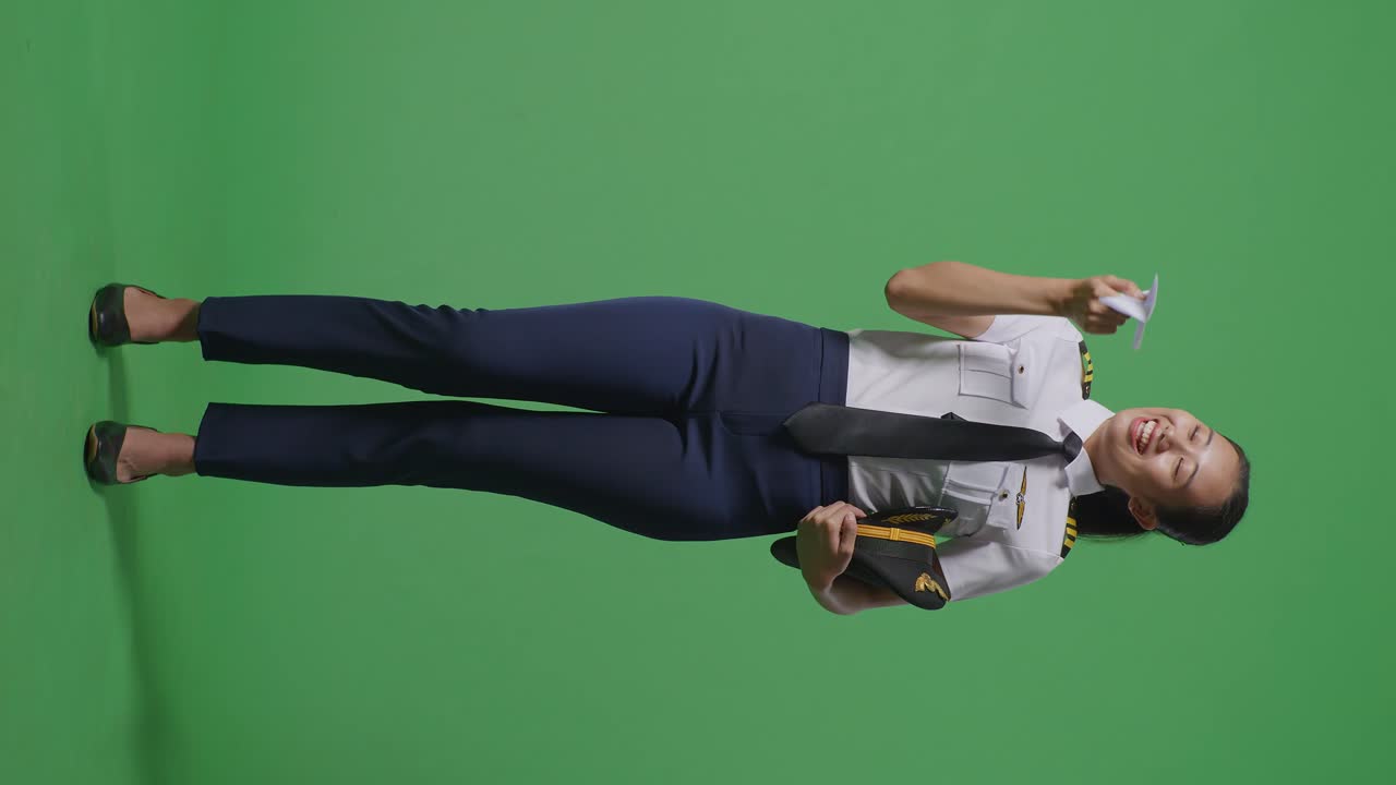 프로 유니폼을 입은 아시아 여성 조종사가 종이 비행기를 발사하고, 제트 모델을 손에 들고, 항공 아카데미 조종사, 녹색 스크린 배경 스튜디오에서 항공기 선장