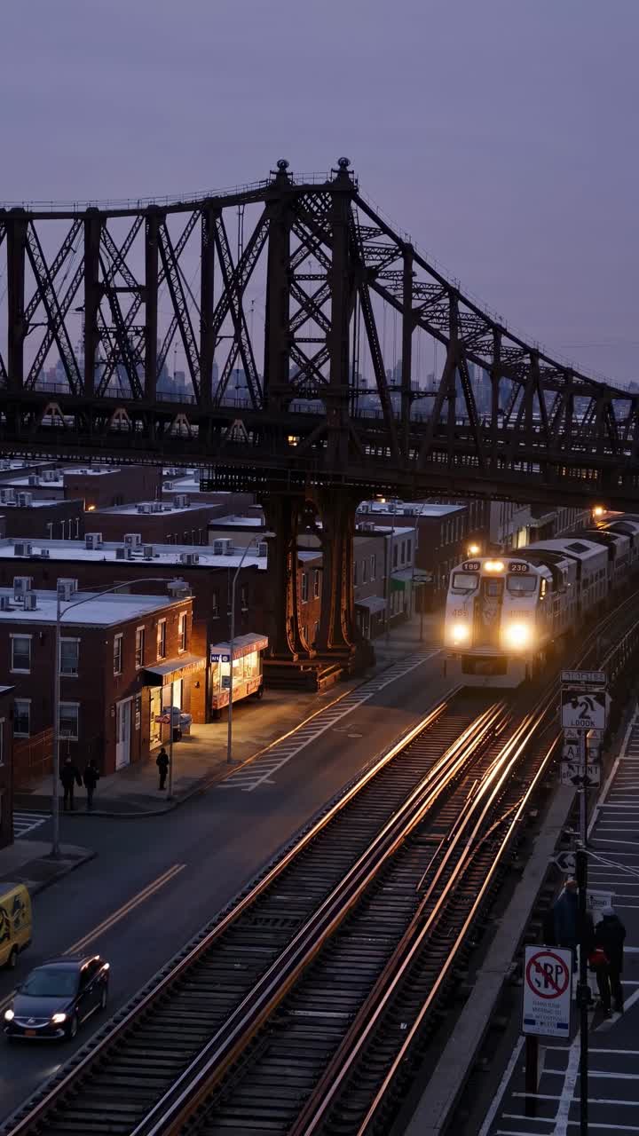 Aerial video captures a train crossing a lit bridge at dusk, highlighting urban architecture
