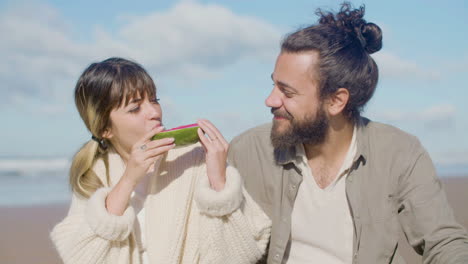una hermosa pareja caucásica disfrutando de un picnic en la orilla del mar.