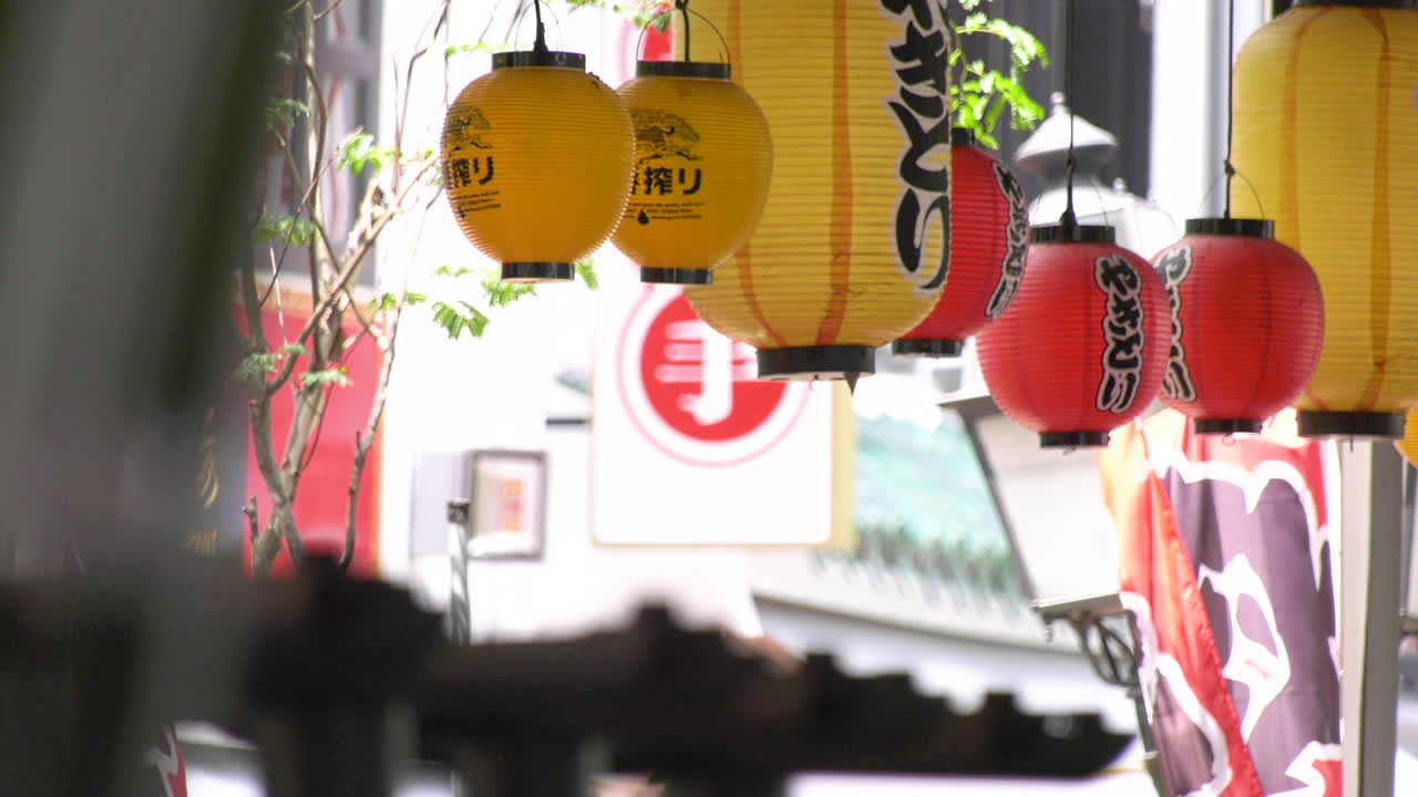 Yellow and red Japanese lanterns blowing in the afternoon breeze at a Japanese restaurant by the Singapore river.